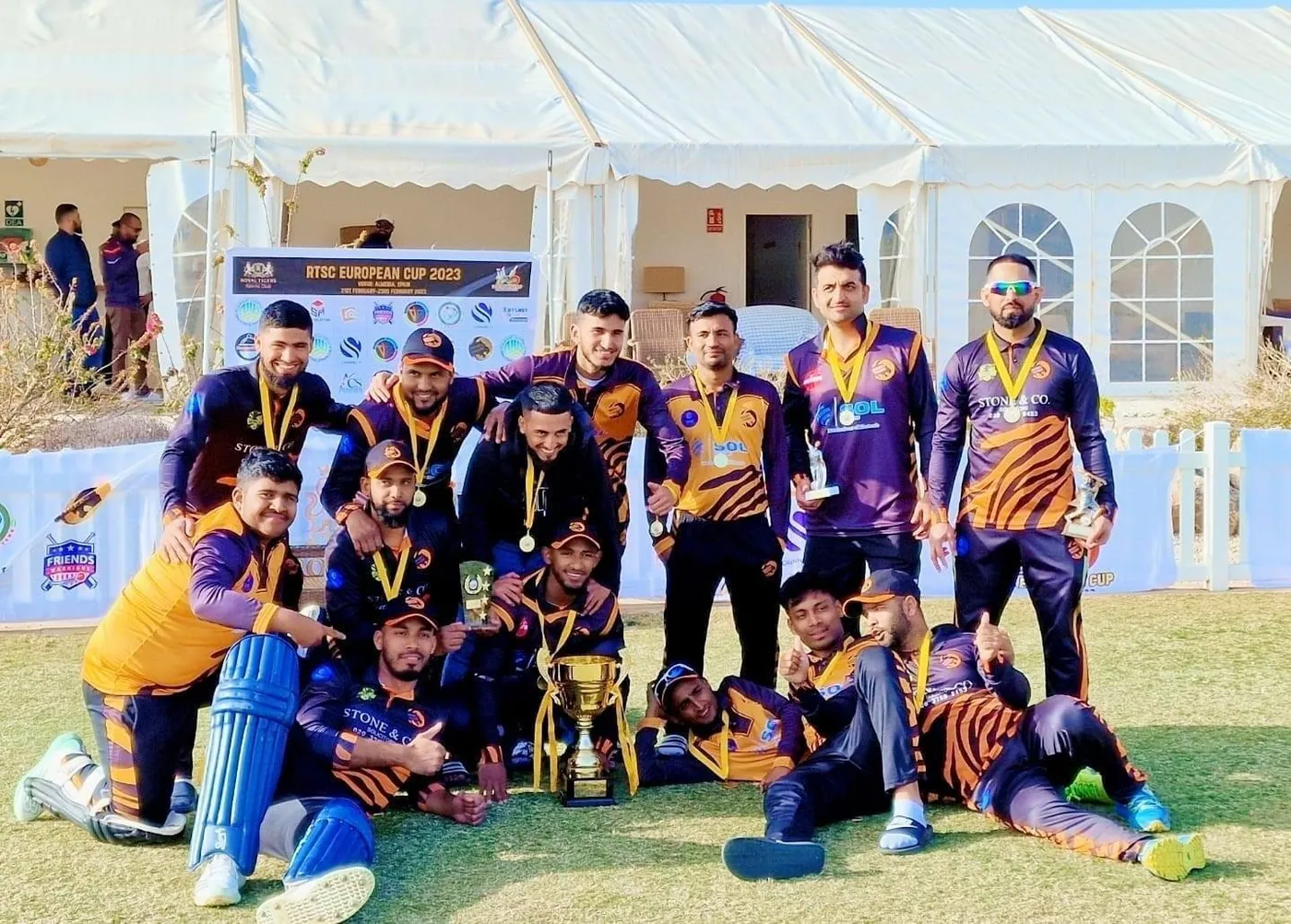 UK Bangla Tigers squad celebrating a cup win with medals and trophy